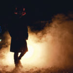 Der rote Puschelhut macht die Maske des Horrorclowns noch absurder