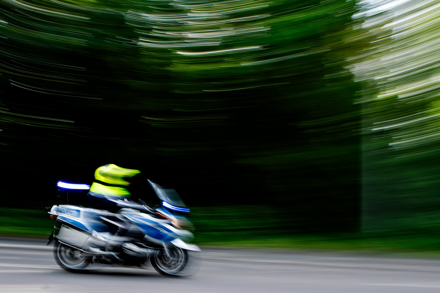 Beim VIVAWEST Marathon - Ein Polizist bolzt auf seinem Motorrad die gesperrte Straße hinunter. Er und seine Kollegen haben die Spitze der Läufer des VIVAWEST-Marathons gesichert.